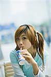 Jeune femme à boire boisson restauration rapide, en regardant la caméra