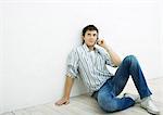 Young man sitting on floor, using cell phone