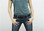 Jeune femme debout avec les pouces dans les poches de jean, gros plan de la partie médiane
