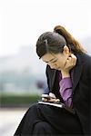 Businesswoman using messaging phone, leaning forward