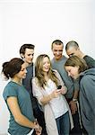 Group of young adult and teenage friends looking at cell phone, white background