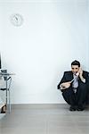 Businessman sitting in corner, talking on telephone