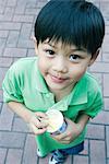 Boy holding sweet snack, smiling at camera