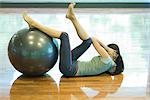 Junge Frau mit den Beinen ruhen auf Fitness-Ball Sit-ups zu tun