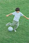 Garçon jouant au soccer sur herbe, vue grand angle, pleine longueur