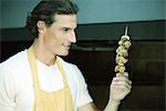 Man holding up grilled kebab