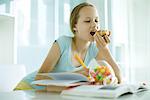 Girl eating sweet snacks and doing homework