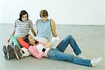 Three teen friends, teen girl reclining on teen boys knees, reading