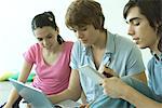 Trois amis adolescents utilisant conjointement, ordinateur portable, une prise de notes