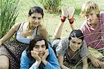 Young friends reclining on grass, smiling at camera