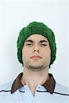 Jeune homme portant knit hat, sillonnant les sourcils, portrait, gros plan