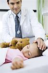 Doctor with hand on sleeping child's head, smiling