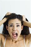 Woman pulling hair and screaming at camera, portrait