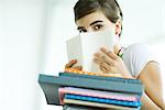 Teen girl avec pile de travail à domicile, se cachant le visage derrière le livre, portrait