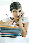 Teen Girl mit Stapel von Hausaufgaben, mit Handy und Notebook schreiben