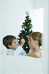 Boy and mother on sofa smiling at each other, Christmas tree in background