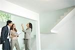 Female real estate agent showing house to young couple, pointing to ceiling