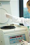 Young female researcher using centrifuge in laboratory, partial view