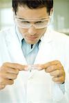 Researcher wearing protective goggles picking up Petri dish