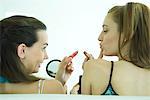 Deux jeunes amis brandissant de rouge à lèvres, une recherche dans la main de miroir, vue arrière