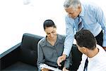 Three business associates looking at file together, one pointing