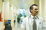 Male doctor looking away, hospital corridor in background