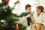 Couple sitting on couch, making a toast with champagne, smiling at each other