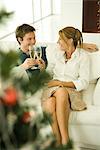 Couple faire toast au champagne, souriant à l'autre, arbre de Noël au premier plan