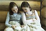 Deux adolescentes dans assis sous des vêtements d'hiver chauds couverture ensemble, lecture