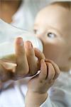 Mother's hand holding bottle while baby drinks, close-up