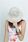 Teenage girl pulling hat over face, portrait