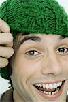 Jeune homme portant knit hat, souriant à la caméra, portrait