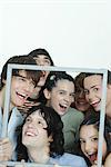 Group of young friends posing for photo, holding up picture frame, laughing, portrait