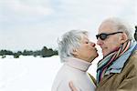 Senior couple standing face to face, kissing, side view