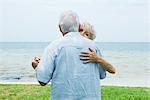 Senior couple dancing on sidewalk overlooking ocean, waist up