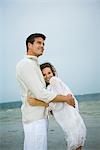 Man and young female companion on beach, embracing