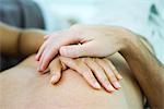 Woman's hand on man's barechest, man's hand on top of hers, cropped view