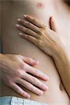 Woman's and man's hands on man's bare torso, close-up, high angle view