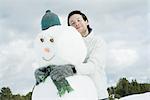 Young man hugging snowman