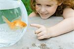 Girl pointing to fish in goldfish bowl