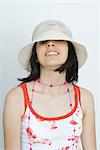 Teenage girl looking at camera from beneath hat, smiling, portrait