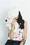 Teenage girl hiding face with stuffed toy, laughing