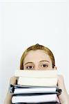 Young woman looking at camera over stack of books