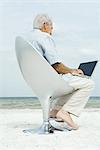 Alter Mann mit Laptop am Strand