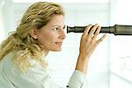 Woman looking through telescope, smiling, profile