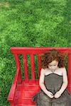 Little girl sitting on bench, eyes closed, high angle view