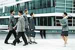 Male and female professionals walking on busy sidewalk, side view