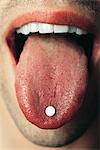 Man holding pill on tongue, extreme close-up