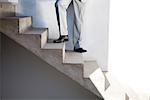 Businessman standing on staircase, low section, low angle view