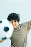 Little boy playing with soccer ball, arms out, smiling at camera